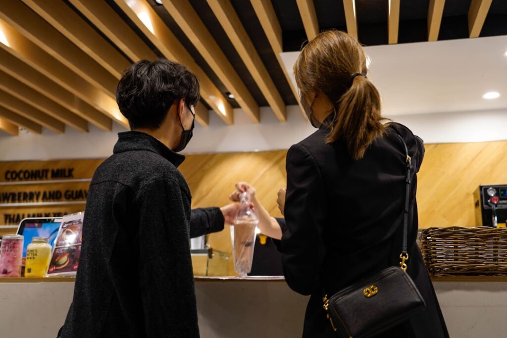 Man and woman in business attire shake hands over a sleek, modern desk in a bright office, symbolizing a successful real e...