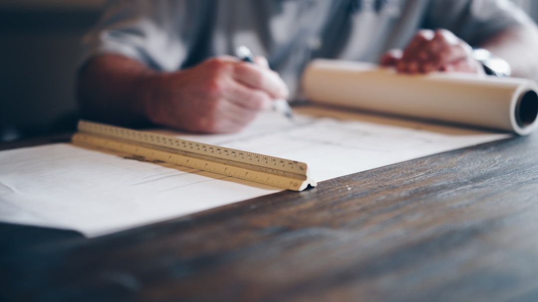 A close-up of a real estate professional's hands pointing to details on a home's architectural blueprint, symbolizing a meticulous, full-service approach.
