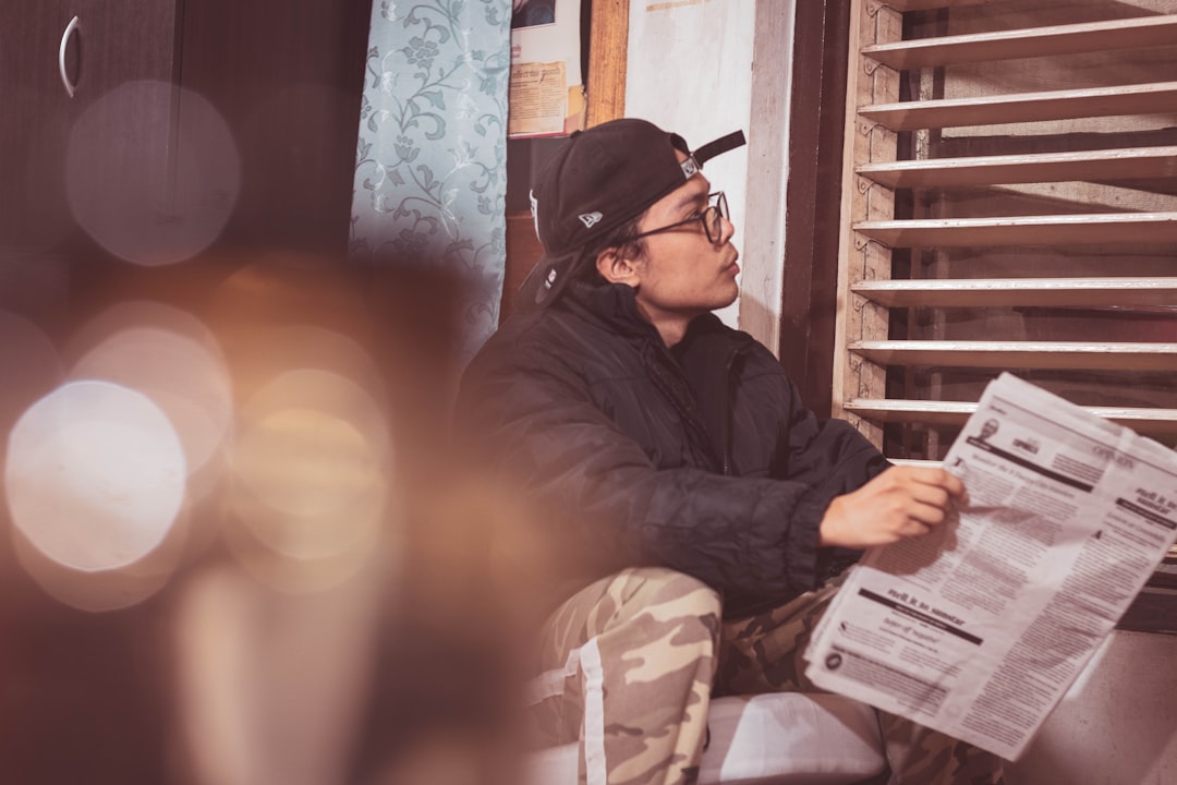A homeowner with a concerned expression sits at a modern dining table reviewing real estate contracts, symbolizing the financial stress of high commission fees.