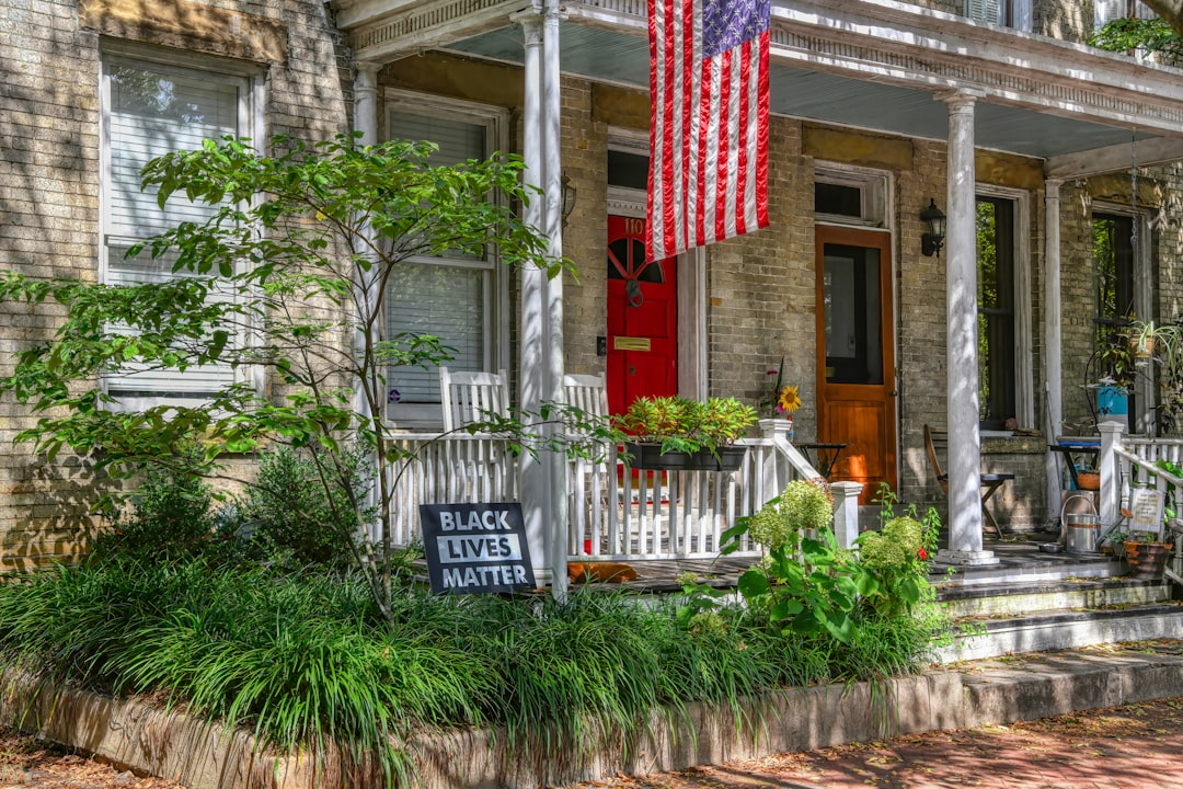 A crisp real estate 'Sold' sign planted in the green lawn of an attractive single-family home, signifying a successful sale and a top-dollar offer.