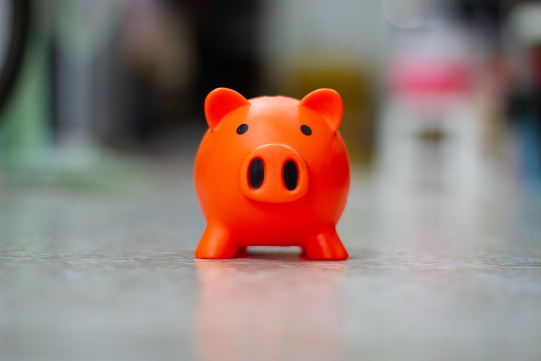 A house key resting next to a white ceramic piggy bank on a clean surface, symbolizing the savings from a 1% real estate listing fee.