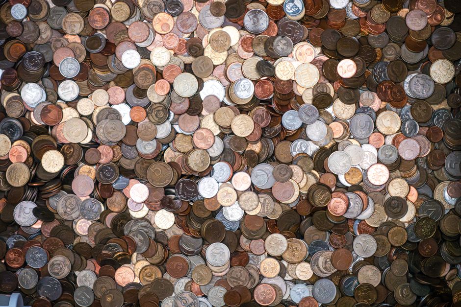 A small green sapling sprouts from a neat stack of coins against a clean, bright background, symbolizing financial growth and turning real estate commission savings into a new investment.