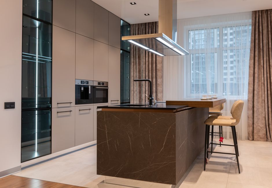 A bright and airy modern luxury kitchen featuring high-end appliances and custom stone accents on a wall or backsplash, conveying unique design.