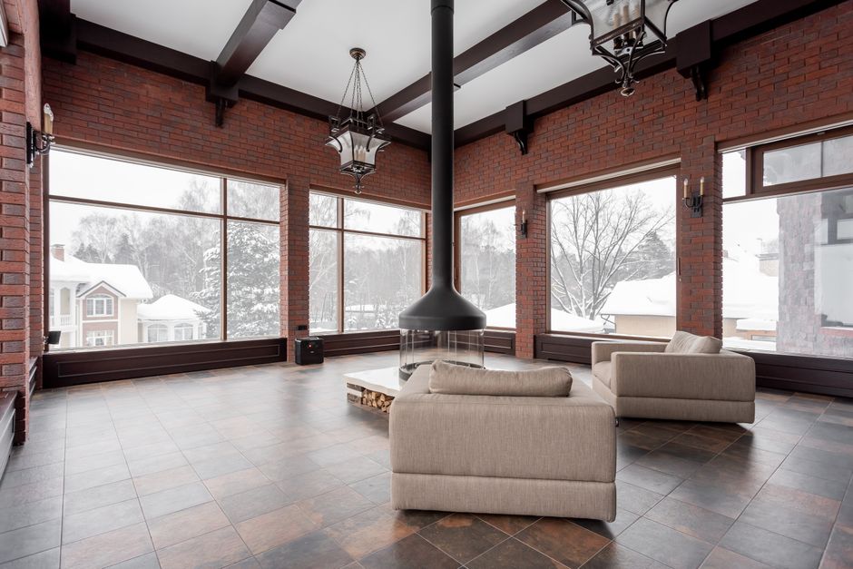 The interior of a modern, upscale living room with a large picture window showcasing a stunning panoramic view of a mountain range.