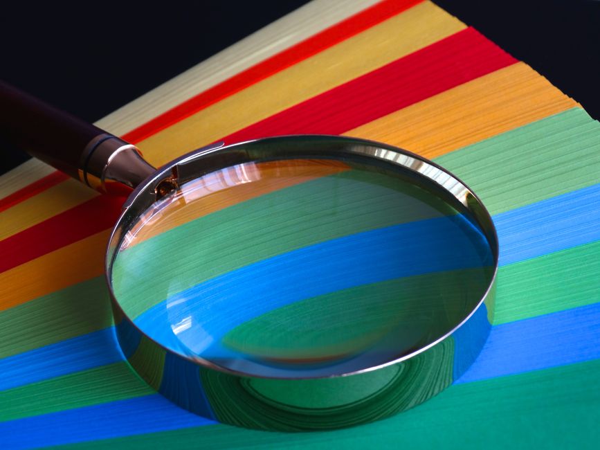 Close-up, brightly lit photo of a magnifying glass held over a set of modern house keys, symbolizing a transparent and clo...