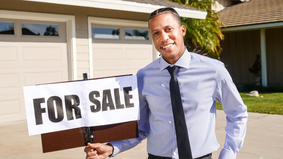A real estate 'For Sale' sign on the manicured front lawn of a welcoming suburban house, symbolizing the home selling process.