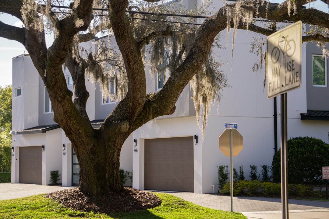 A real estate 'Sold' sign is prominently displayed in the green front yard of a beautiful suburban home, symbolizing a successful and profitable sale.