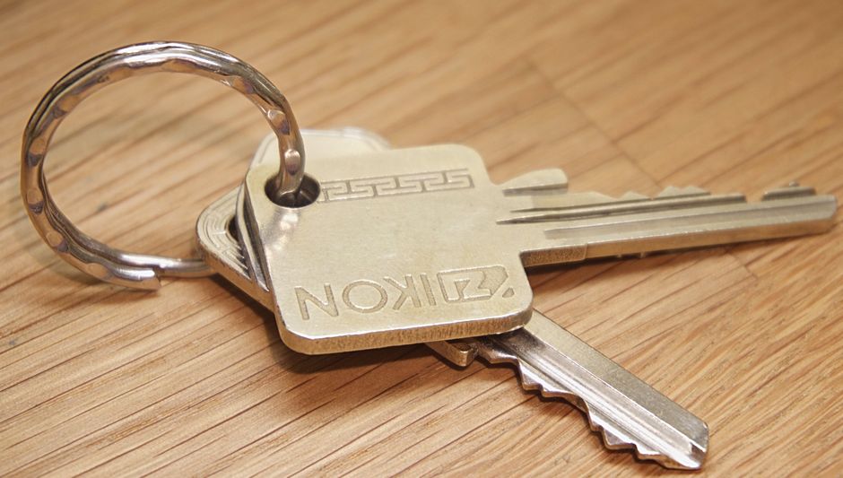A single, elegant house key resting on a minimalist white marble countertop, representing the simplicity and value of a smart real estate transaction.